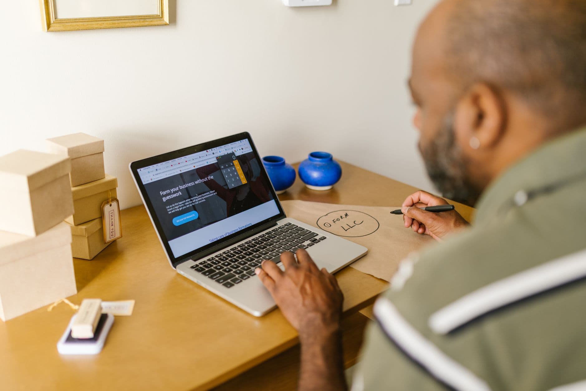A small business owner smiling while working on a laptop in a cozy office.