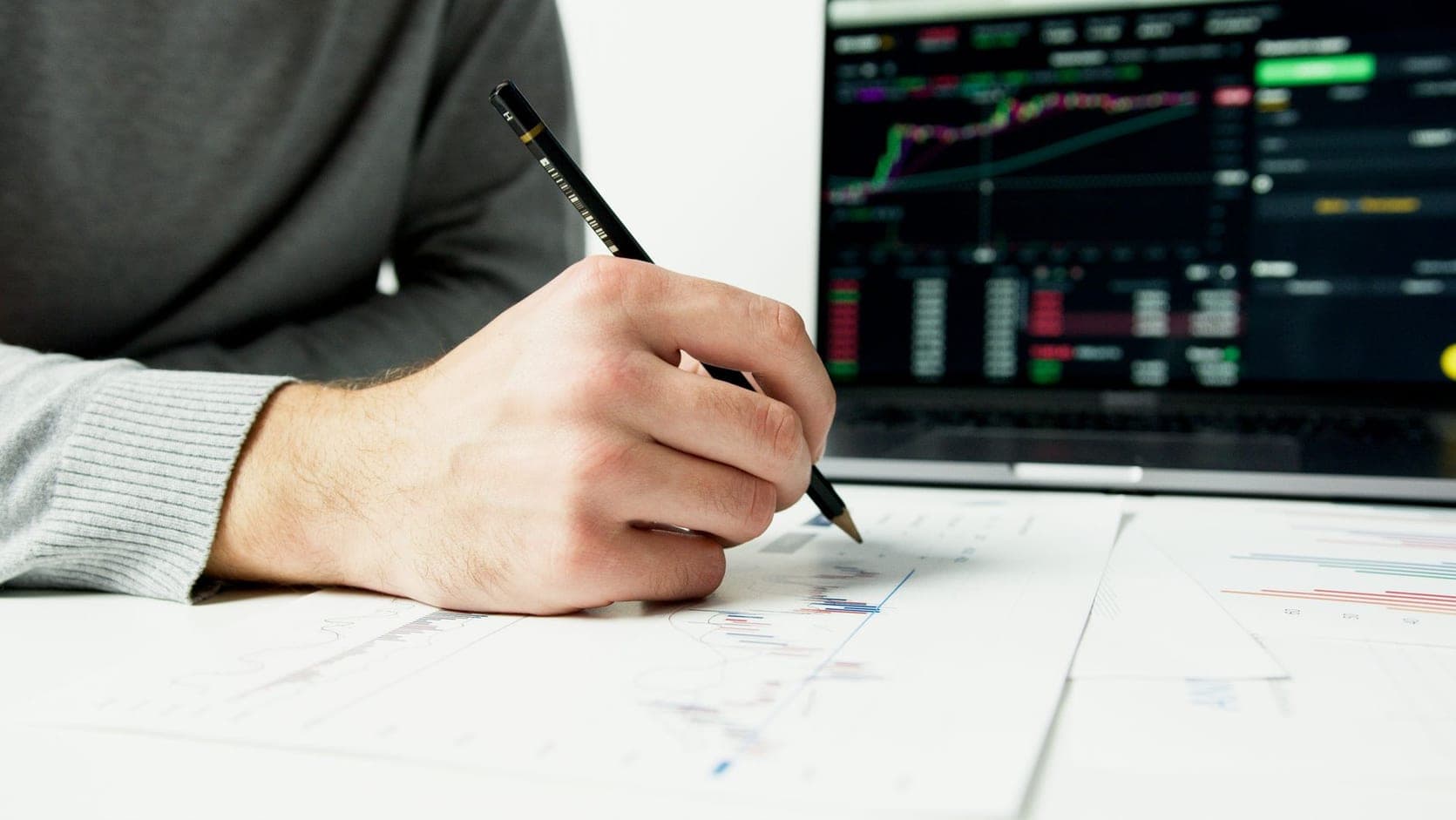 A close up of hands holding a tablet showing colorful bar graphs and pie charts.