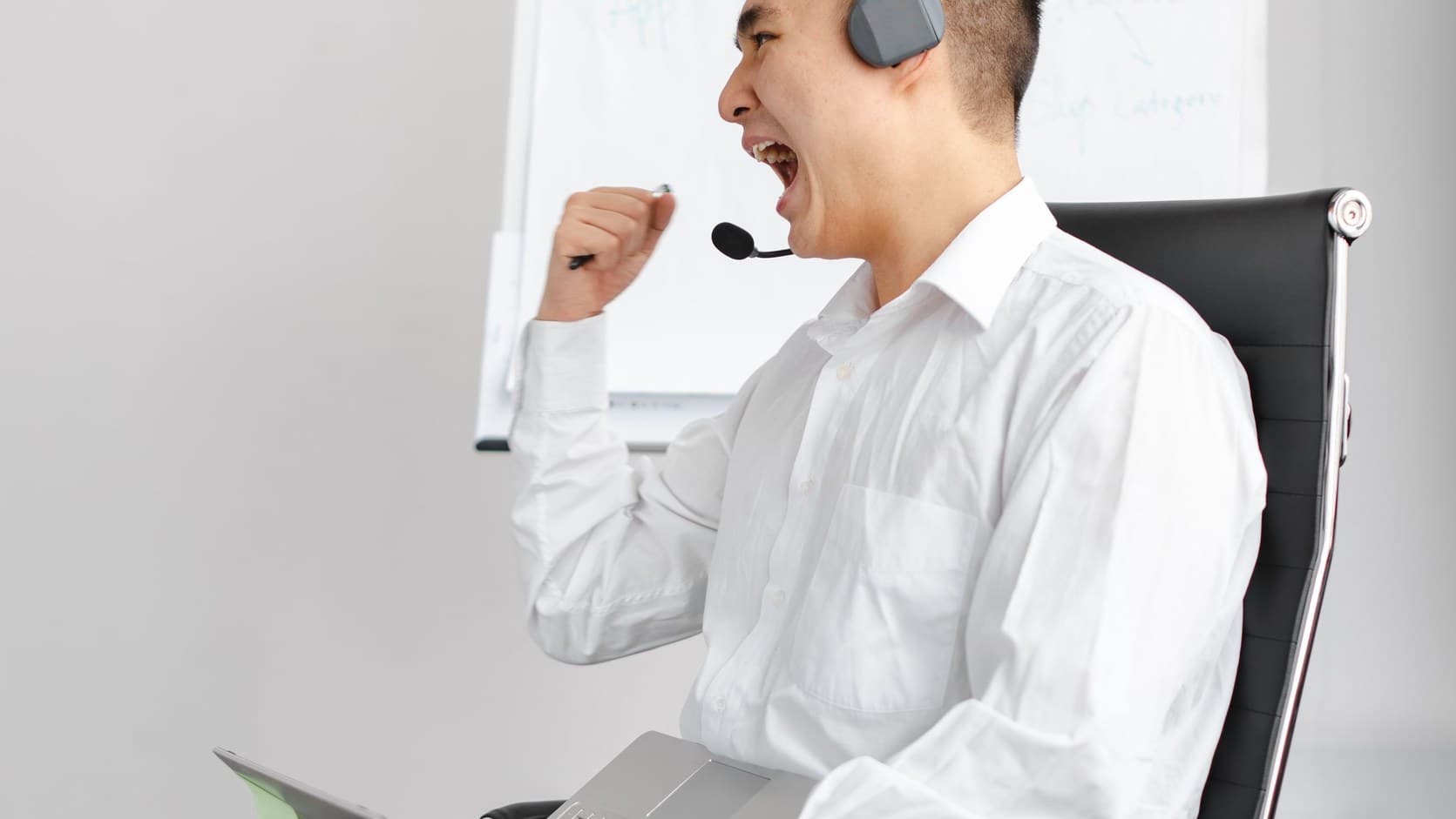 Sales representative with a headset celebrating after closing a deal